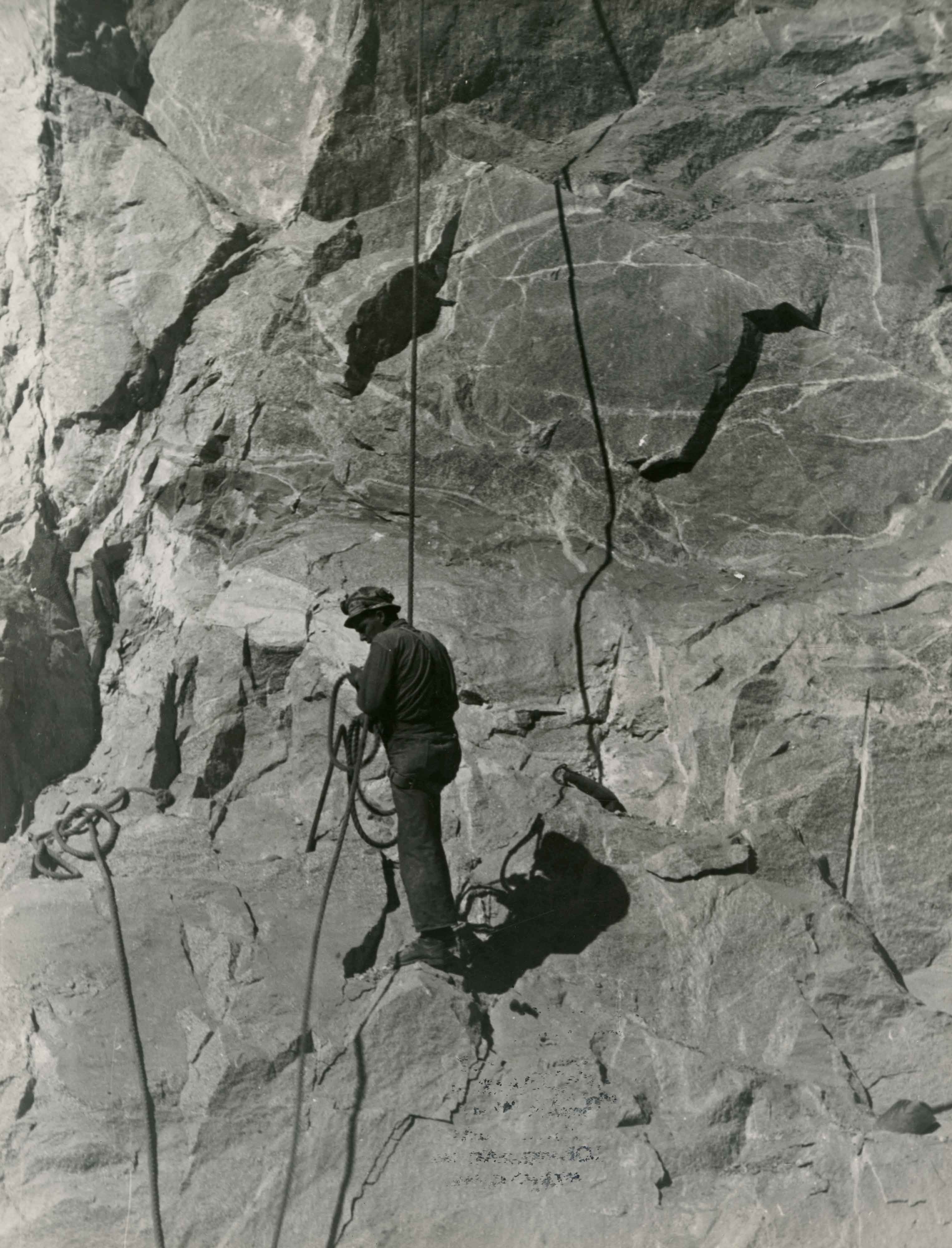 Scaler scales granite cliffs to clean off loose rock and debris. Courtesy of San Francisco Public Library.